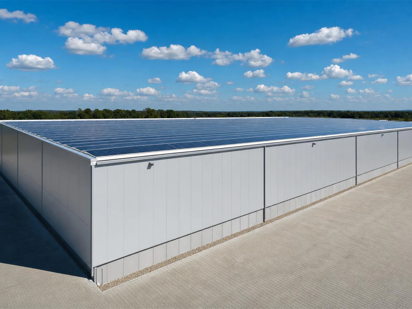 Techo industrial cubierto de paneles solares con el recorrido de la energía señalado: de los paneles al inversor, la batería intercambiando con el inversor, y de ahí al tablero y al consumo.